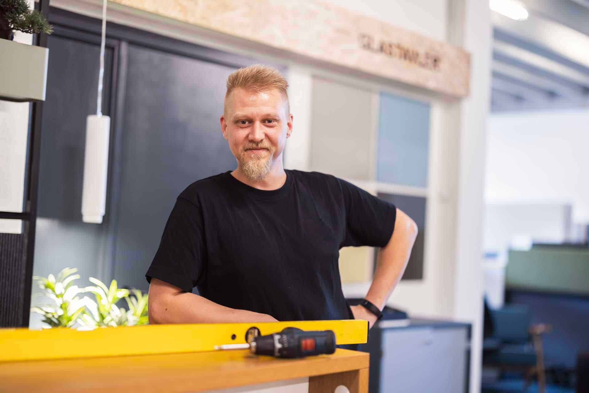 Montør bag skranke med gult vaterpas og skruemaskine i showroom